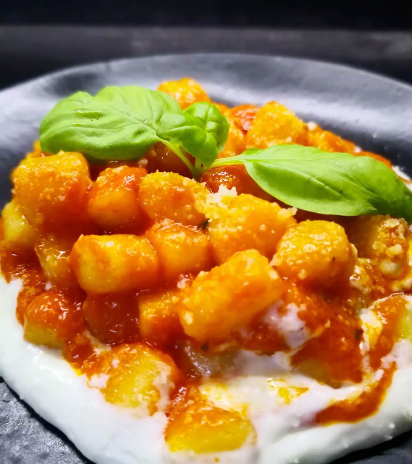 Mini gnocchi con tomate y albahaca sobre una crema de queso burrata fría.