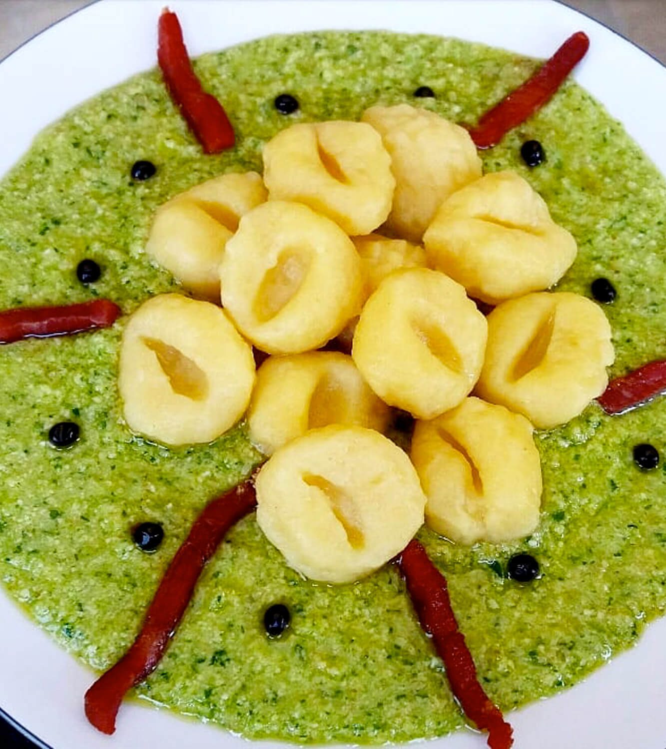 papas Gnocchi di sobre pesto de calabacín y rúcula, perlas de vinagre balsámico y palitos de speck