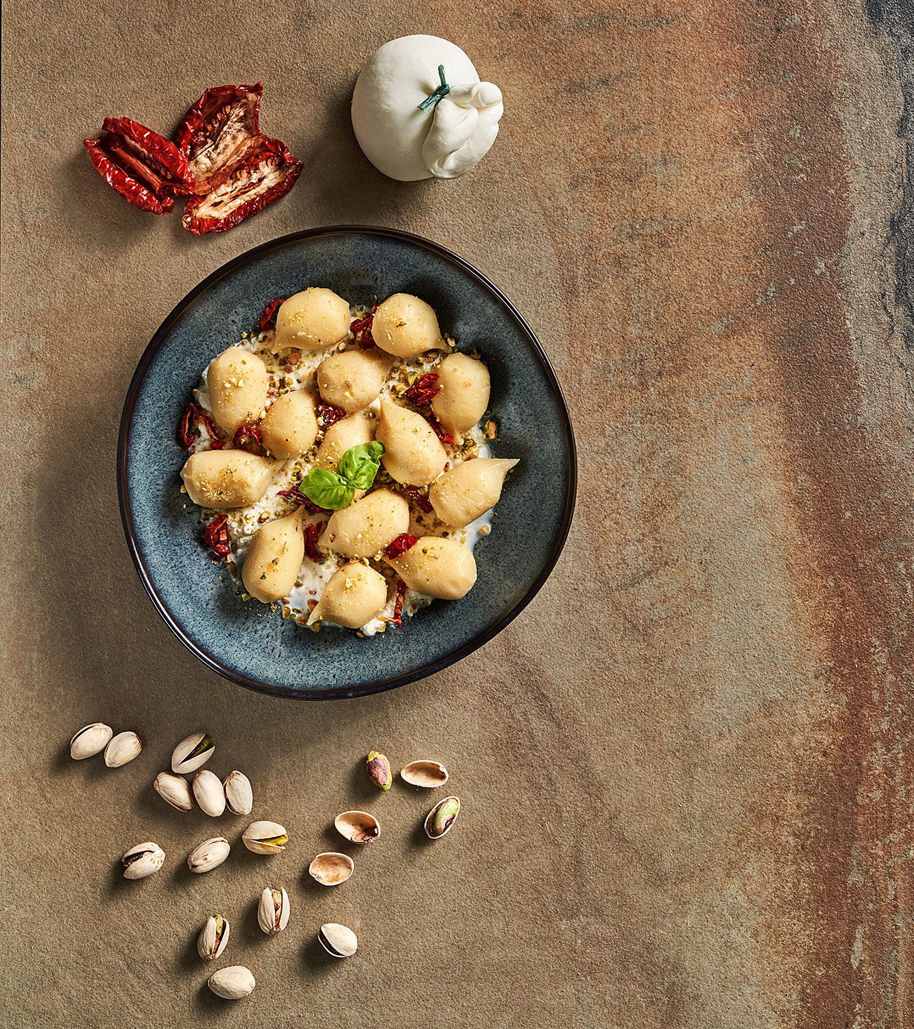 Potato gnocchi filled with tomato and mozzarella cheese, with burrata cheese, sun-dried tomatoes and chopped pistachios